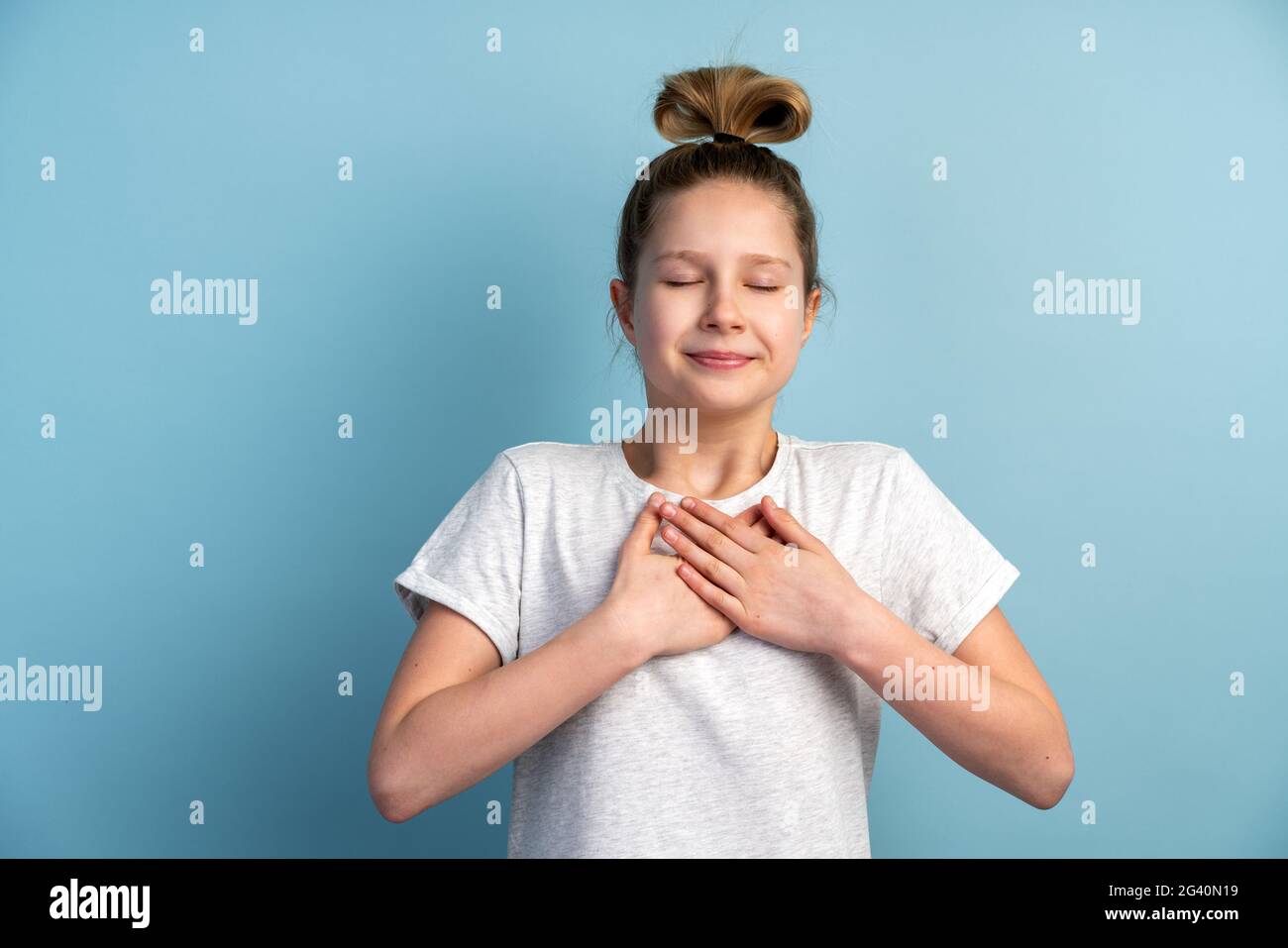 La ragazza teen, sincera e sorridente, mostra un gesto dal cuore, anima. Bella bambina gesturing su una parete di sfondo giallo, copia spazio. Foto Stock