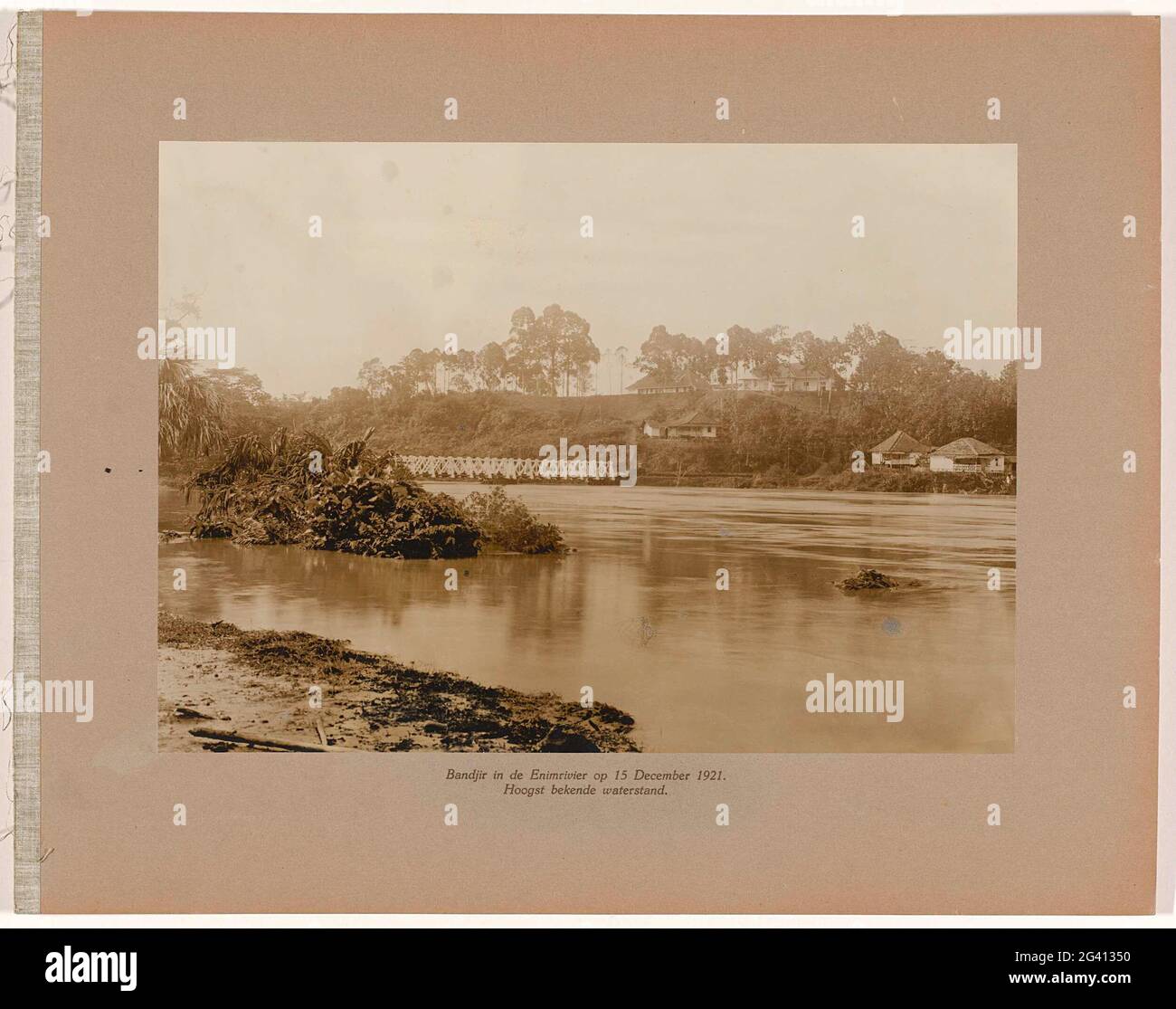 Bandjir nel fiume enim il 15 dicembre 1921. Livello dell'acqua molto noto. Alta acqua (bandjir) nel fiume Air enim il 15 dicembre 1921, in lontananza il ponte ferroviario, alcuni edifici sulla riva sul lato opposto. Parte dell'album fotografico a foglia sciolta offerto dal personale delle miniere di carbone Boekit-ASAM a Sumatra sul direttore tecnico di separazione H. Tromp il 7 gennaio 1922. Foto Stock