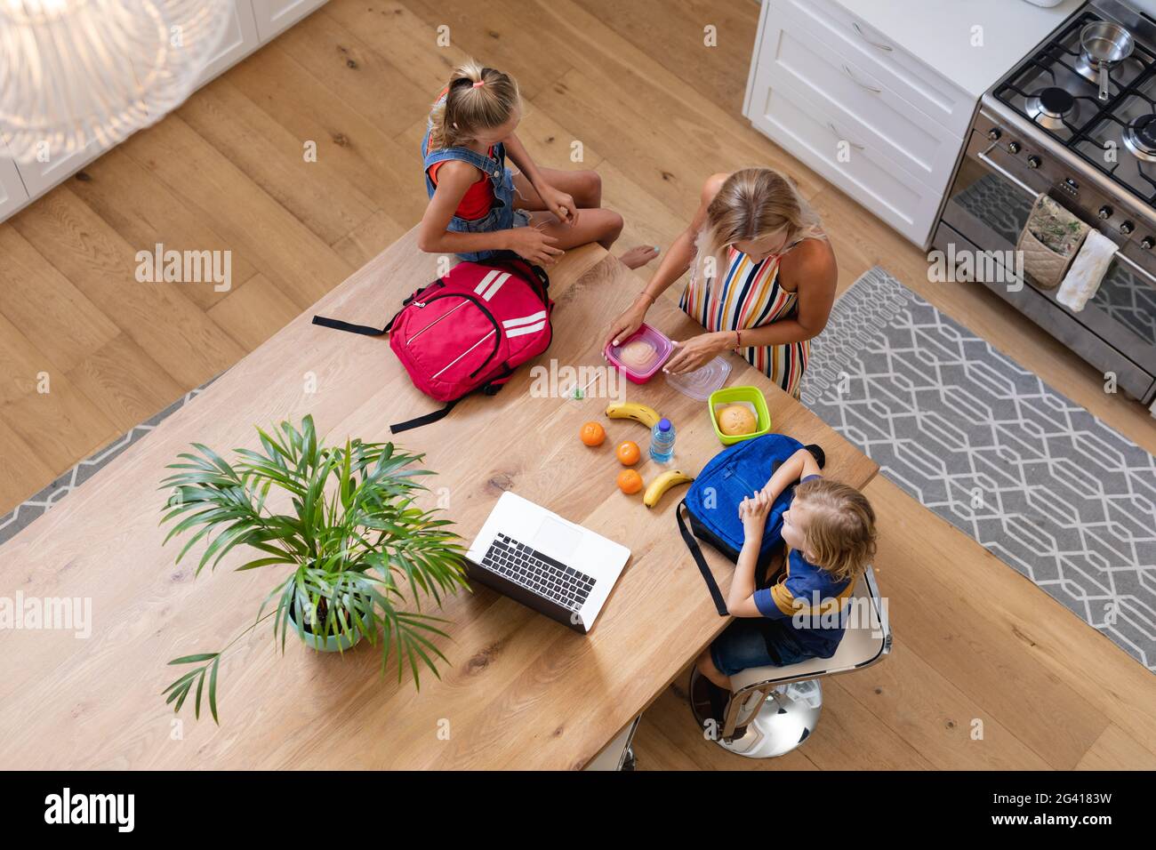 Vista ad alto angolo della madre caucasica con figlio e figlia preparazione di pranzi al sacco in cucina Foto Stock