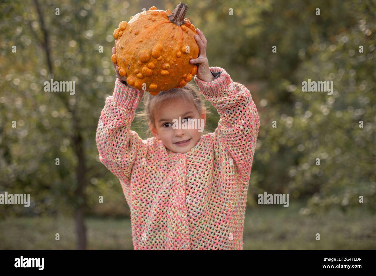 Zucca arancione deformata nelle mani di un bambino. Foto Stock