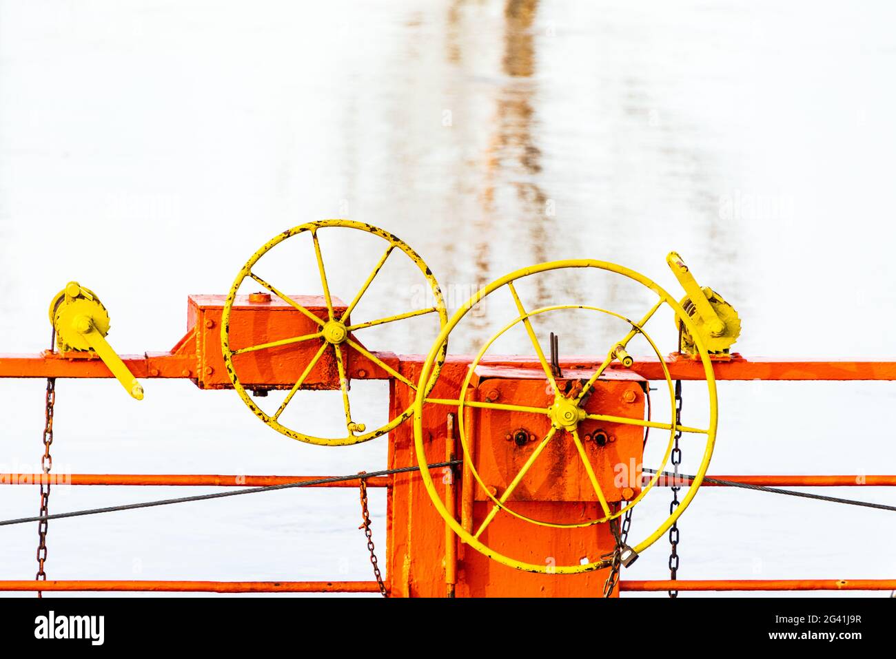 I dettagli del traghetto che attraversa un fiume da cavi collegati ad entrambe le sponde. Il traghetto a catena arancione, il volante giallo e l'acqua blu Foto Stock