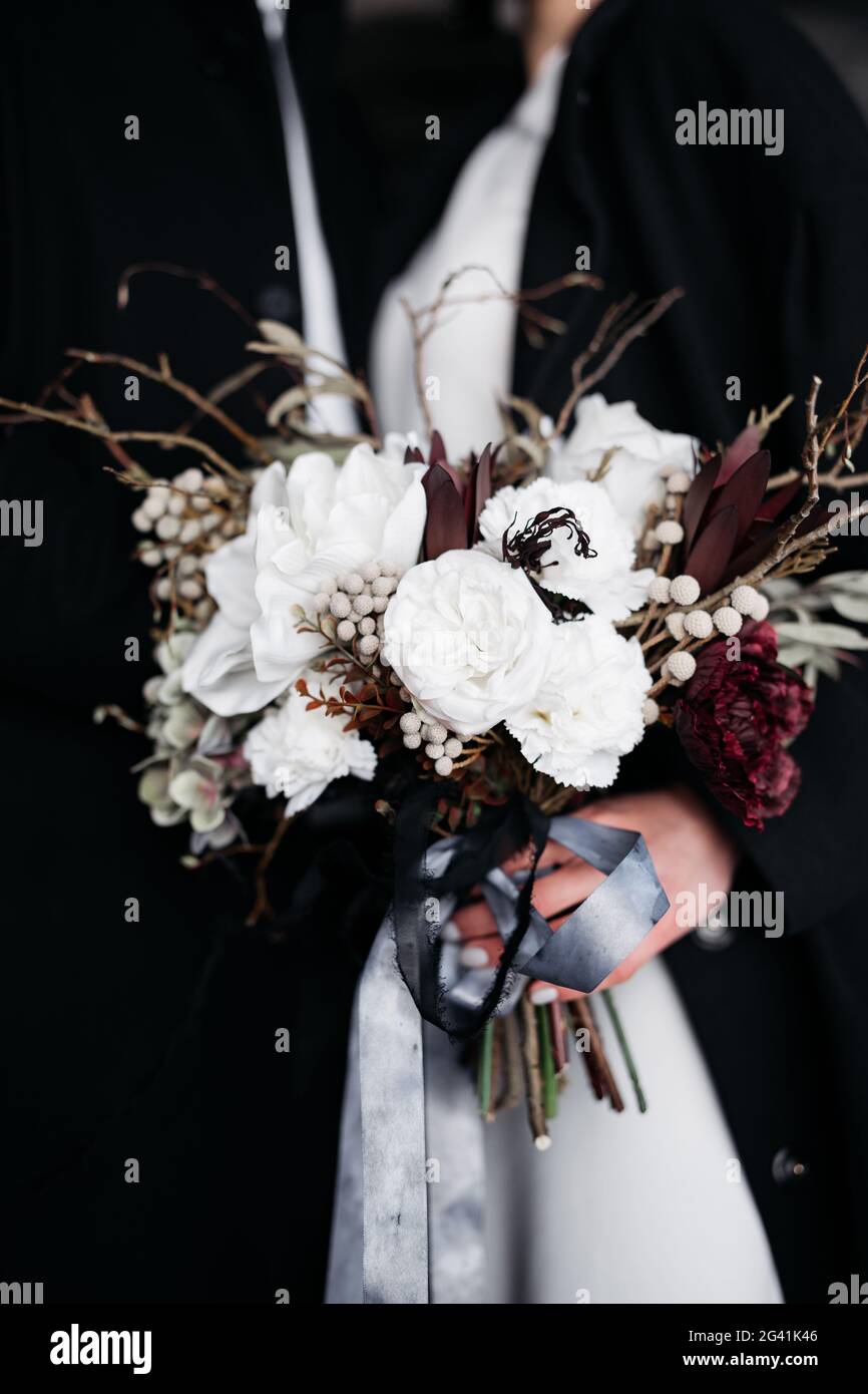 Primo piano di un bouquet bianco con nastri di seta, su fondo nero, nelle mani della sposa. Destinazione Islanda matrimonio. Foto Stock
