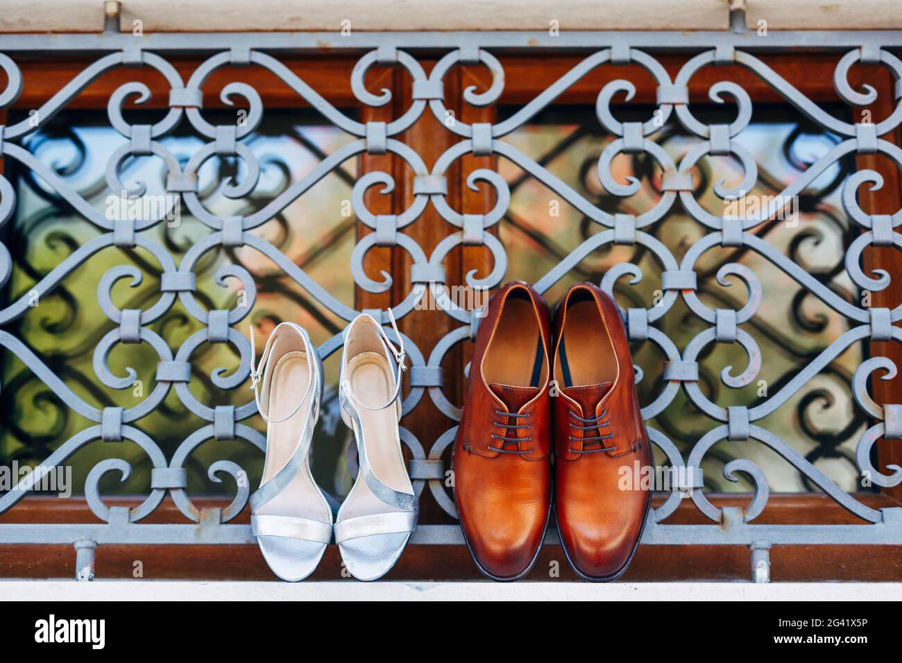 Nuove scarpe da uomo marroni con sandali bianchi da donna sulla finestra all'esterno della griglia in metallo. Foto Stock