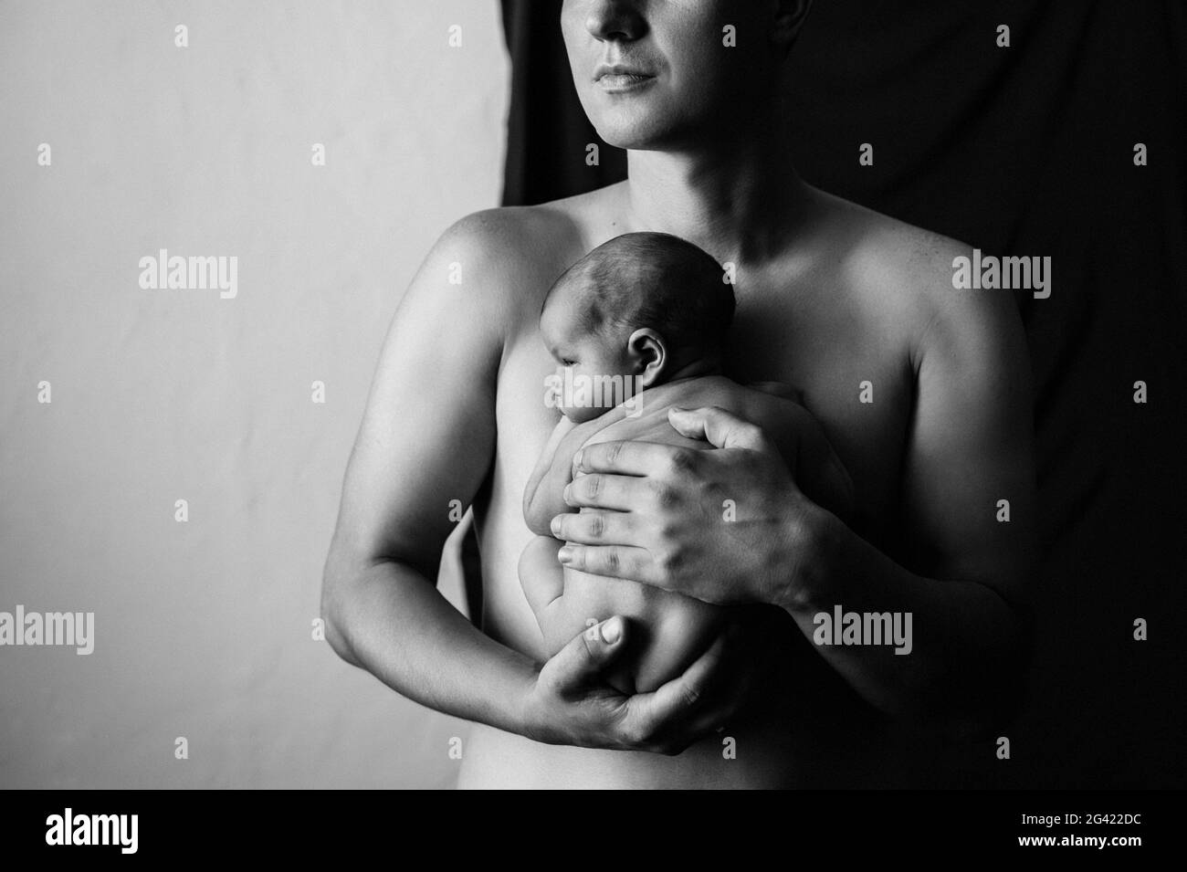 Padre che tiene il suo figlio neonato su sfondo nero Foto Stock