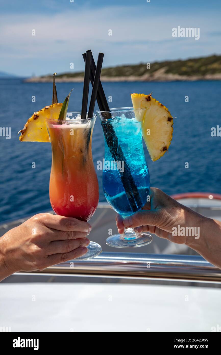 Dettaglio di due cocktail colorati nelle mani dei passeggeri a bordo della nave da crociera, Vis, Vis, Spalato-Dalmazia, Croazia, Europa Foto Stock