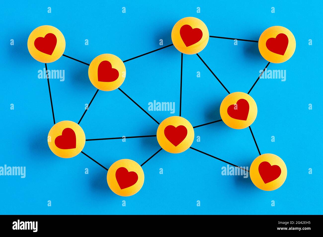 Icone d'amore su palle da ping-pong collegate tra loro che rappresentano una rete sociale. Interazione di rete sociale o concetto di datazione in linea. Foto Stock