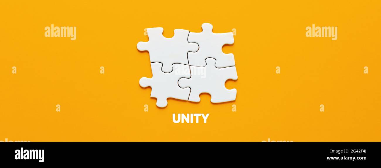 Quattro pezzi di puzzle collegati tra loro con la parola unità. Concetto di unità, sinergia, integrazione o solidarietà. Foto Stock
