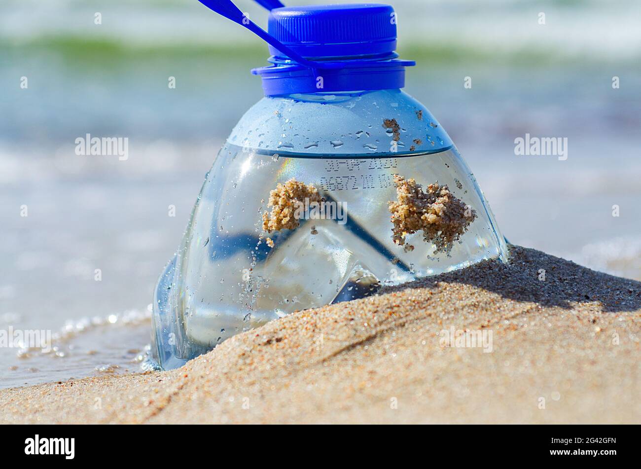 Bottiglia di plastica nella sabbia da spiaggia. Inquinamento del concetto di oceani. Immondizia a terra. Problema di riscaldamento globale. Bottiglia d'acqua dolce al mare. Foto Stock