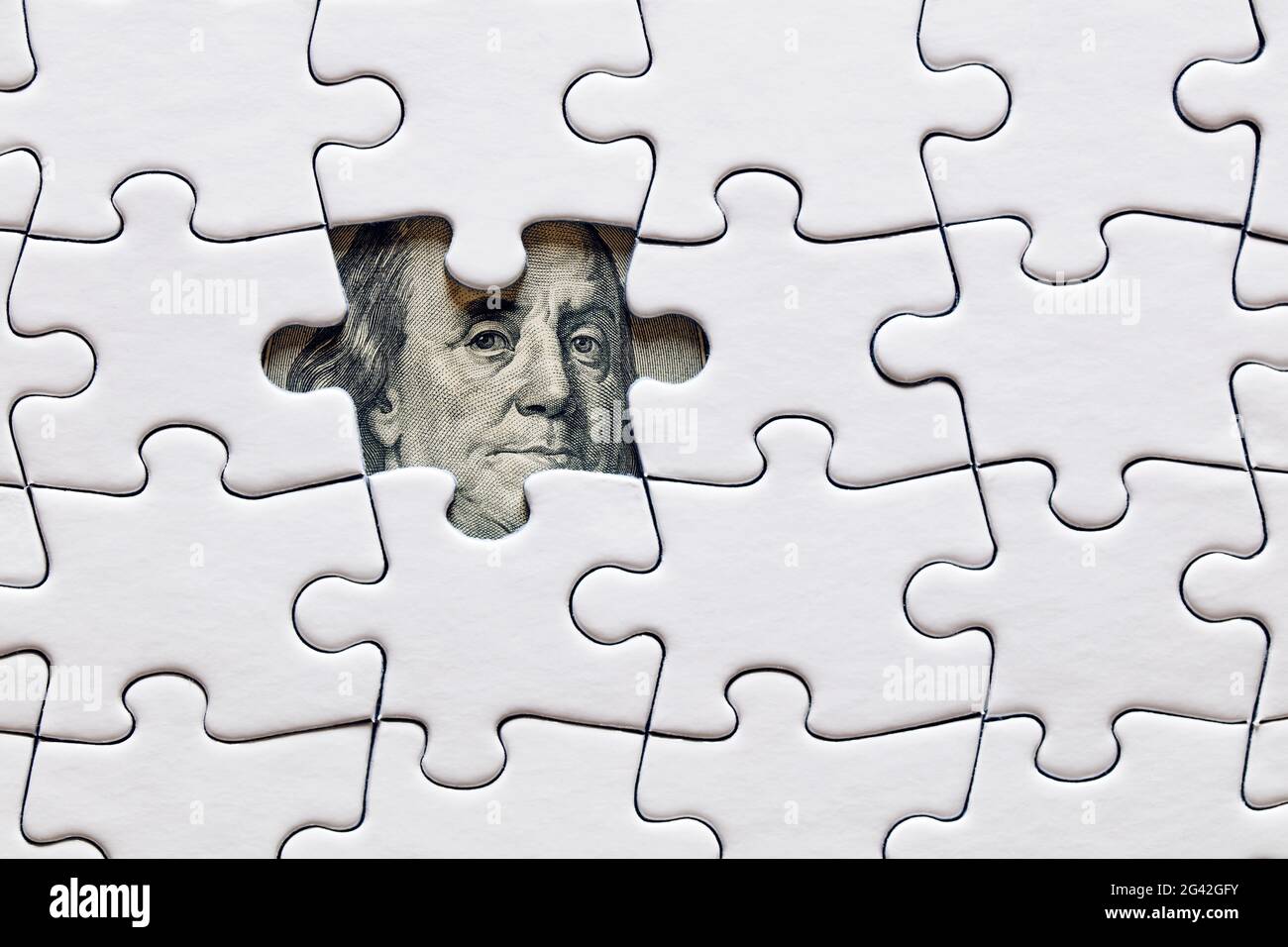 La faccia di Benjamin Franklin da un becco di cento dollari tra pezzi di puzzle assemblati. Turbolenze economiche o finanziarie, incertezza o svalutazione. Foto Stock