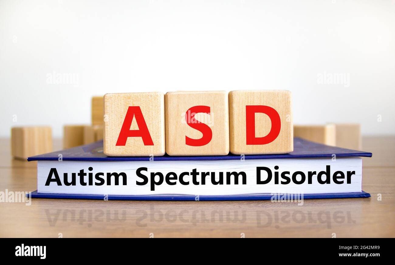 ASD, simbolo di disturbo dello spettro autistico. Cubetti di legno su libro con le parole 'ASD, disturbo dello spettro autistico'. Sfondo bianco. Medico e ASD, autismo spect Foto Stock