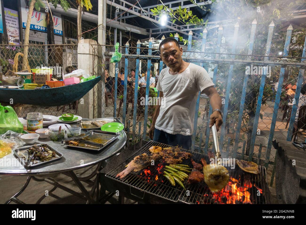 L'uomo grigliava pesce fresco, carne e verdure al No Name BBQ nel Villaggio di Ong Lang, Ong Lang, Isola di Phu Quoc, Kien Giang, Vietnam, Asia Foto Stock
