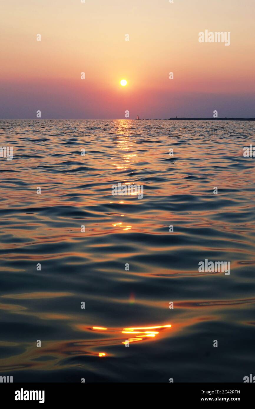 Tramonto soleggiato sul mare che si estende fino all'orizzonte Foto Stock