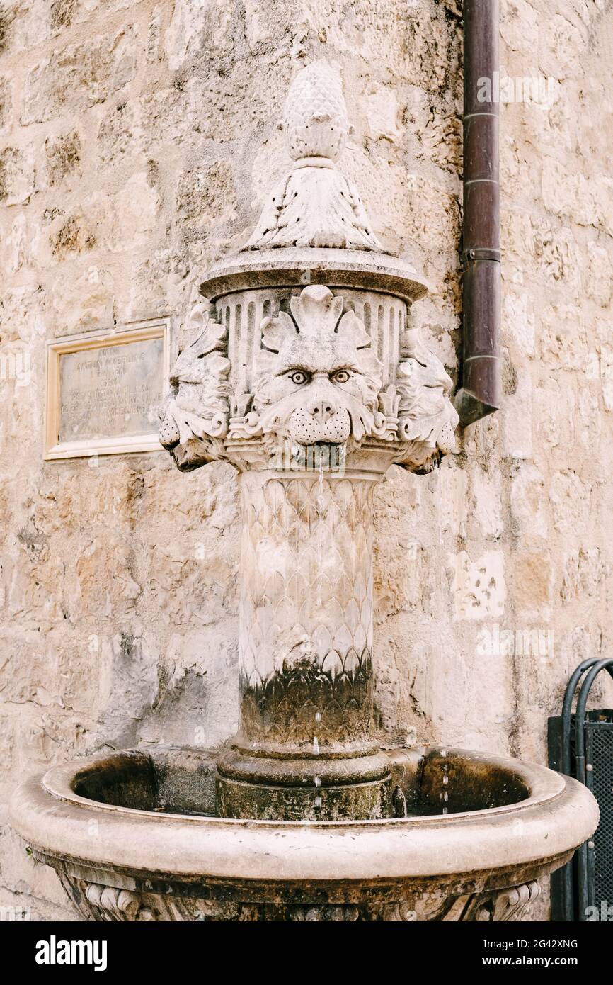 Primo piano piccola fontana all'angolo dell'edificio, in una piazza nella città vecchia di Dubrovnik, Croazia. Una vecchia pietra da bere Foto Stock