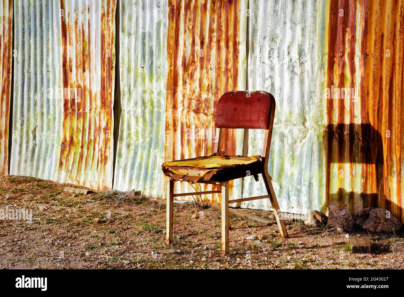 Vecchia sedia di legno di fronte al muro di metallo arrugginito, California, Stati Uniti Foto Stock