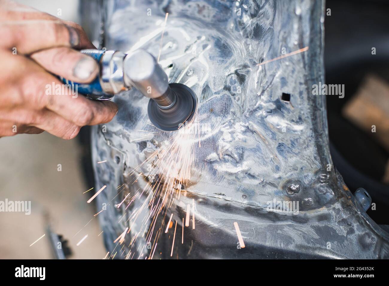 Lavorazione del metallo con un utensile di rettifica elettrico a una profondità di campo poco profonda. Le scintille volano nel processo Foto Stock