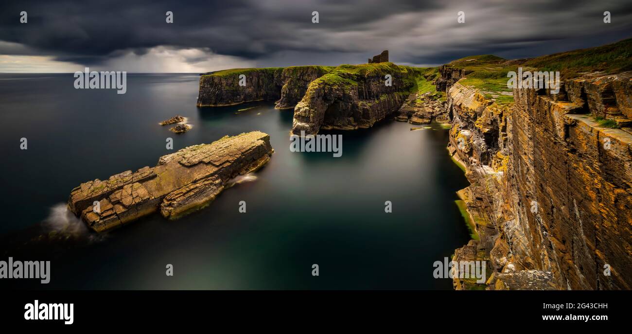 Scogliere costiere e Old Wick Castle sotto il cielo drammatico, Highlands, Scozia, Regno Unito Foto Stock