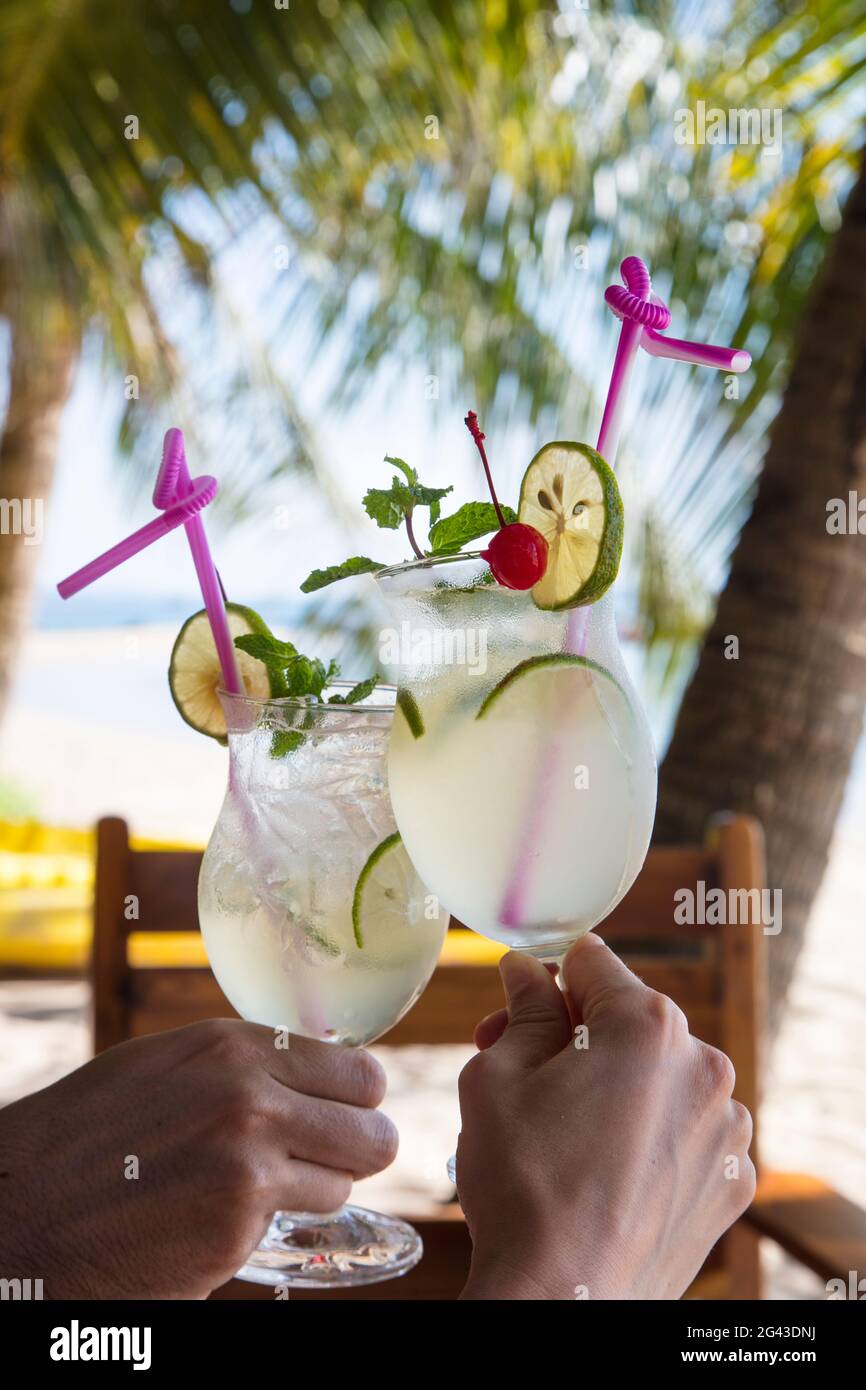 Mani che tengono due bicchieri da cocktail con succo di lime fresco nel ristorante e bar dell'Ancarine Beach Resort a Ong Lang Beach, Ong Lang, Phu Quoc Foto Stock