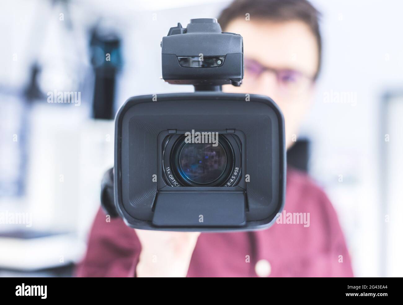 Produzione professionale di film: Il regista maschile sta registrando con una videocamera professionale. Primo piano dell'obiettivo della fotocamera. Foto Stock