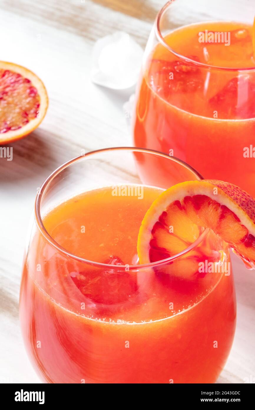 Primo piano cocktail arancione con arance di sangue su un tavolo di legno Foto Stock