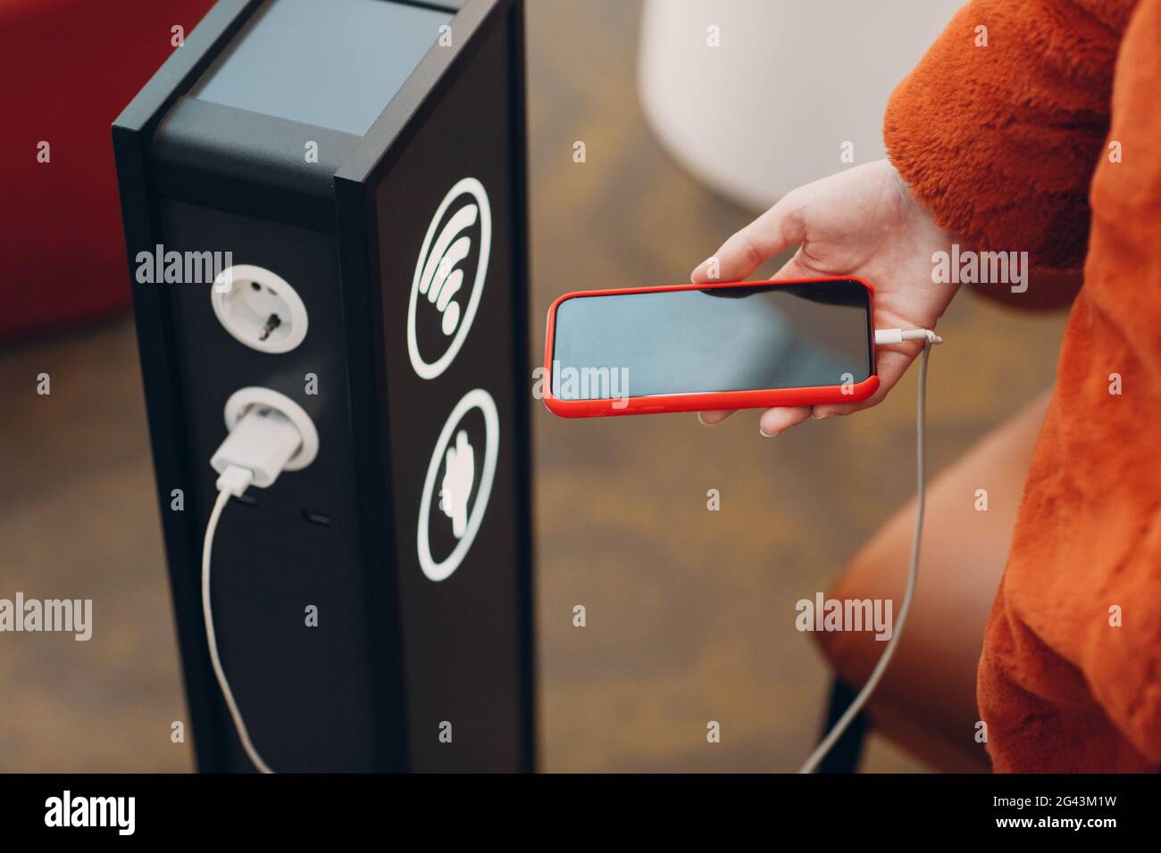 La donna tiene il telefono cellulare in mano sullo sfondo del supporto per la ricarica e il wi-fi Foto Stock