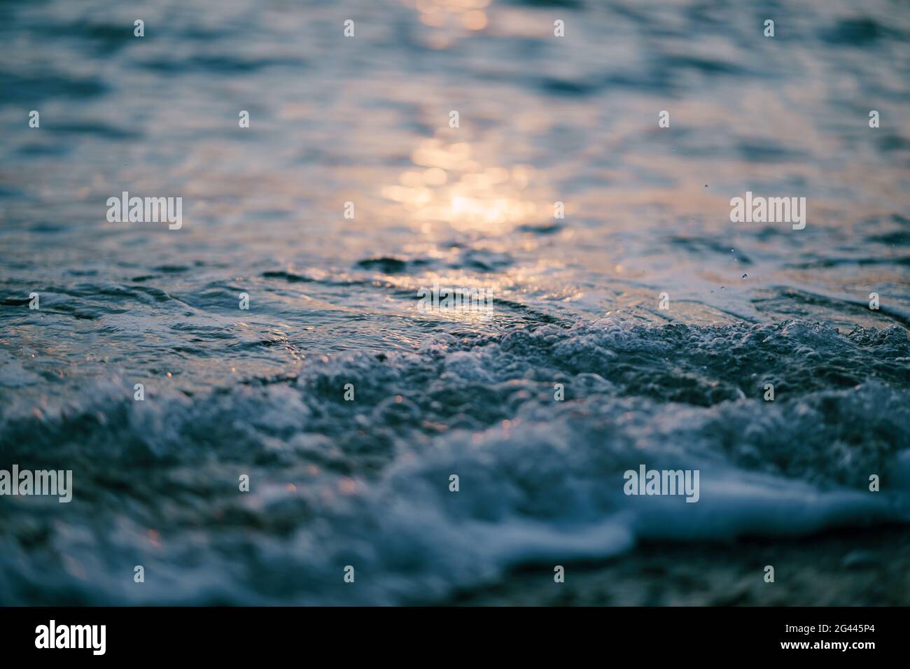 Le onde del mare corrono l'una sull'altra al tramonto Foto Stock