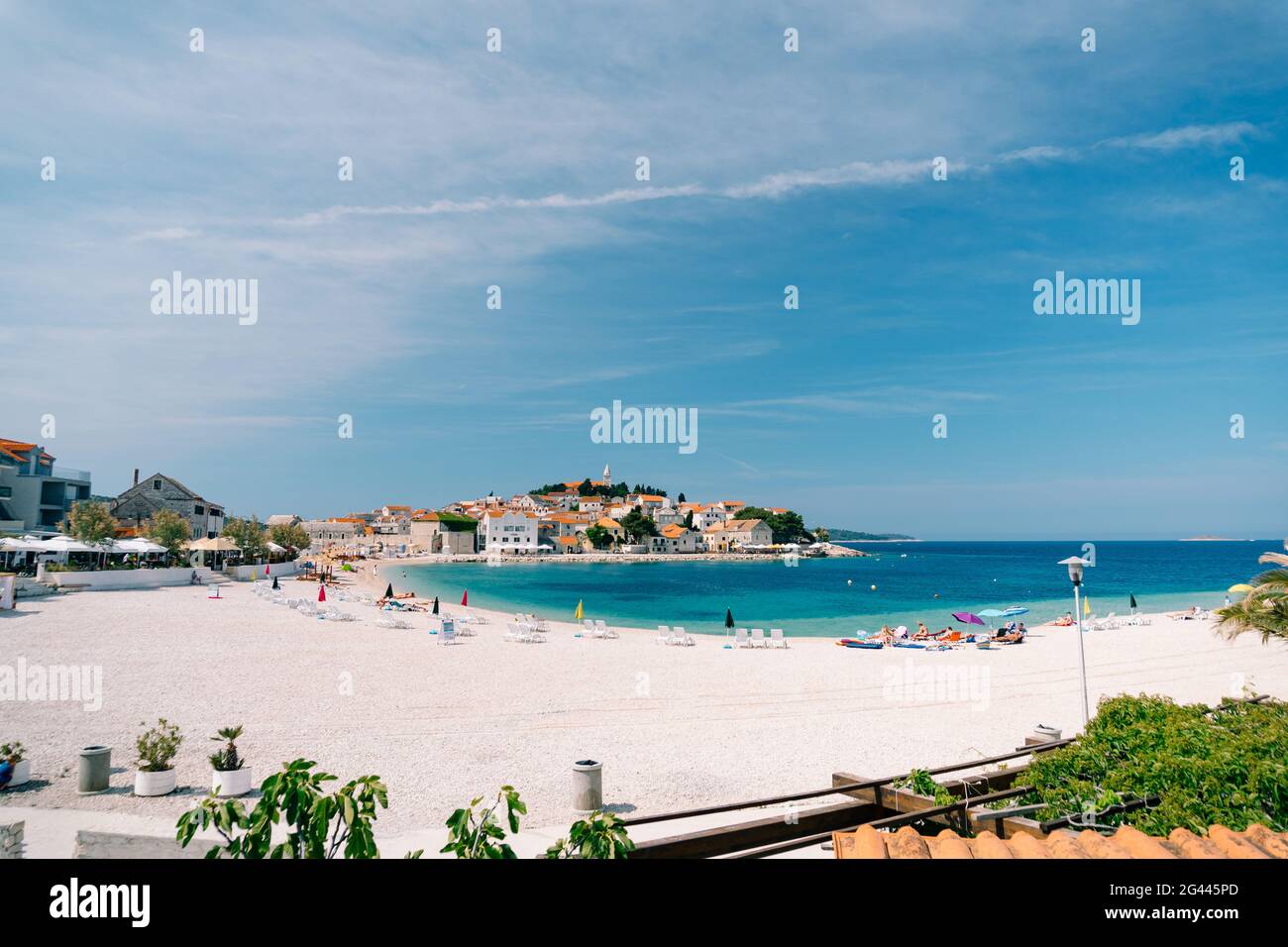 Spiaggia urbana di Primosten città con la gente che ha un riposo sullo sfondo di splendidi edifici e cielo blu Foto Stock