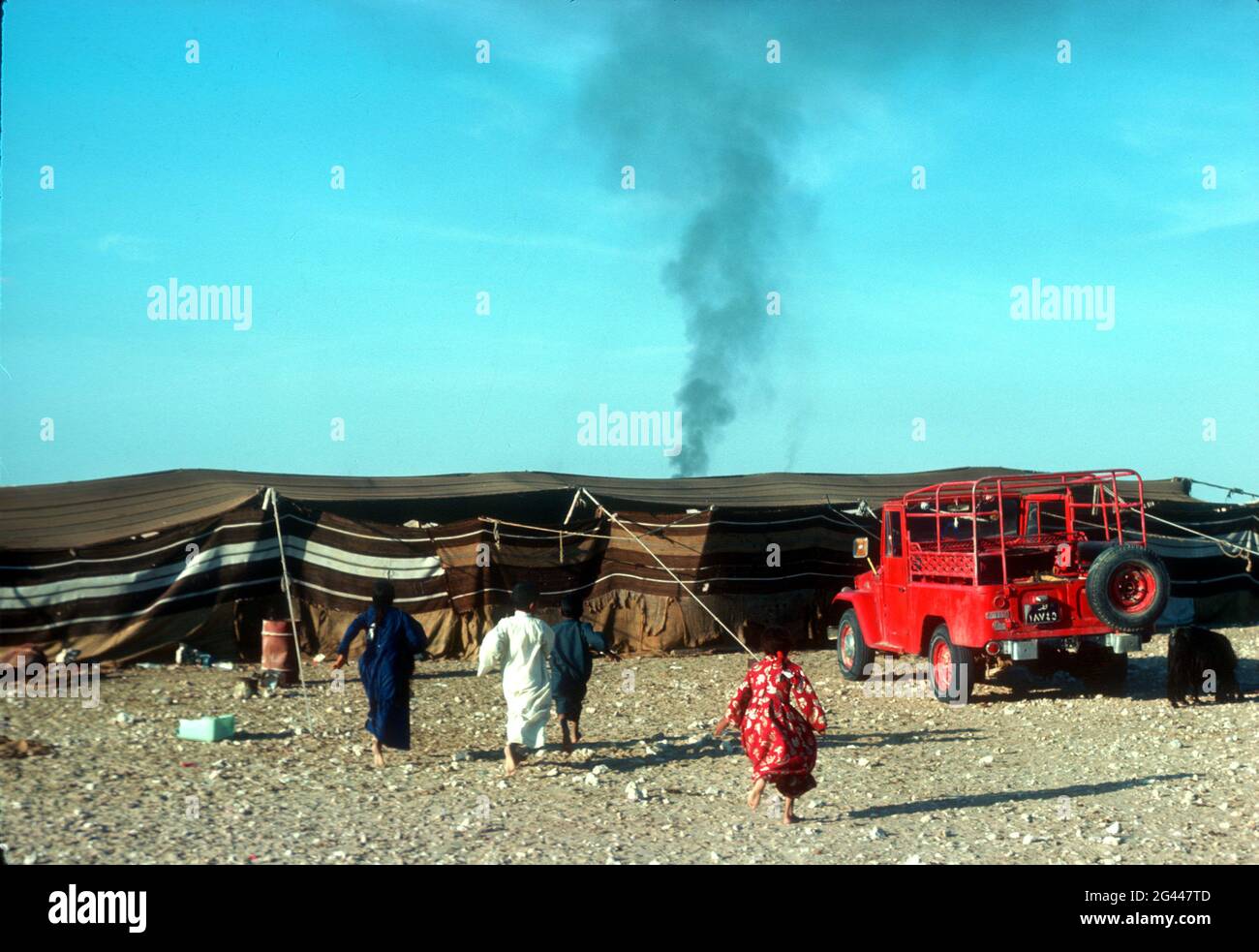 Chiamati dalle loro madri, i bambini corrono all'interno della loro tenda. Campo beduino, Kuwait centrale 1976. Foto Stock