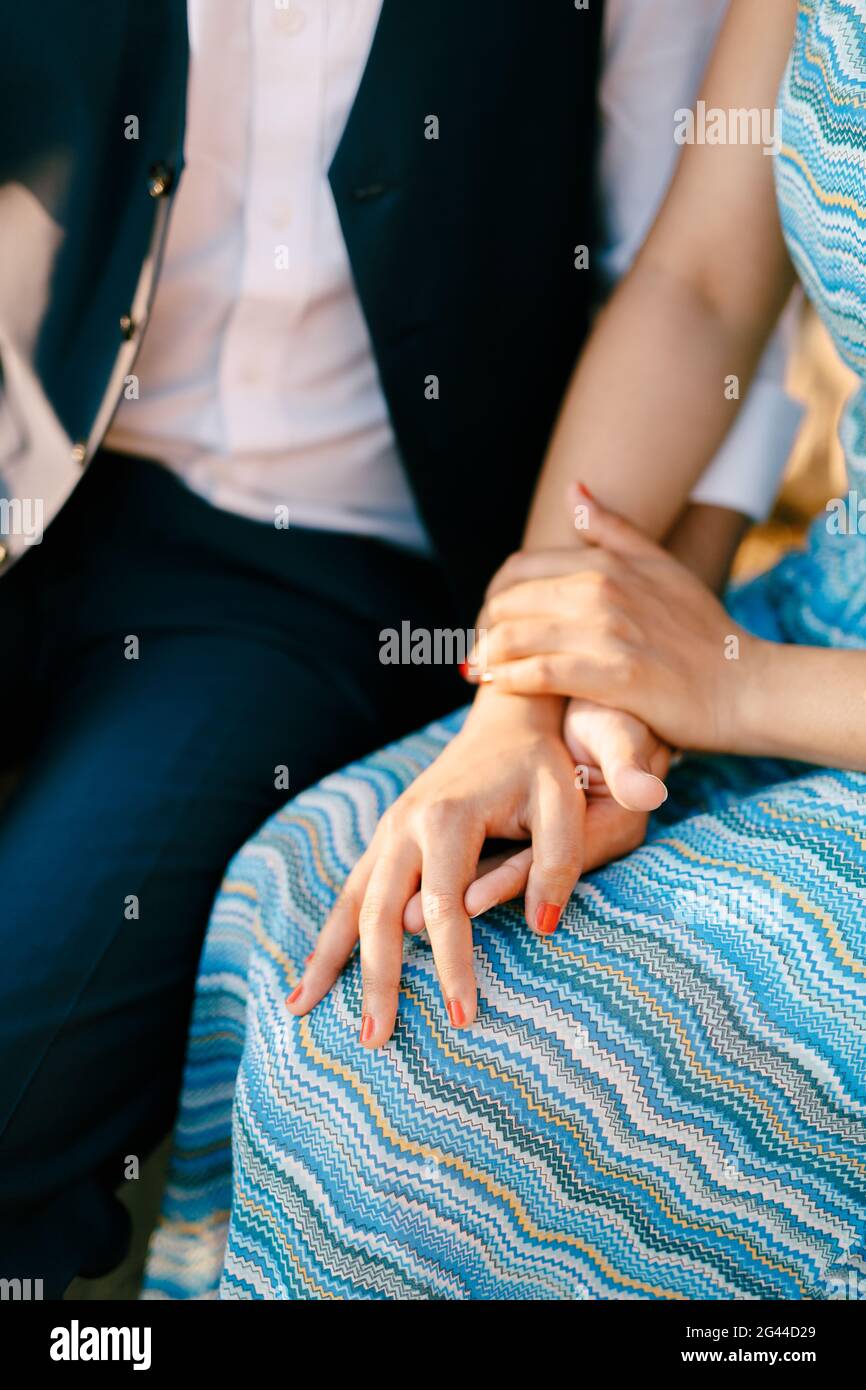 Uomo in abito e donna in un blu a righe gli abiti sono seduti tenendo le mani Foto Stock