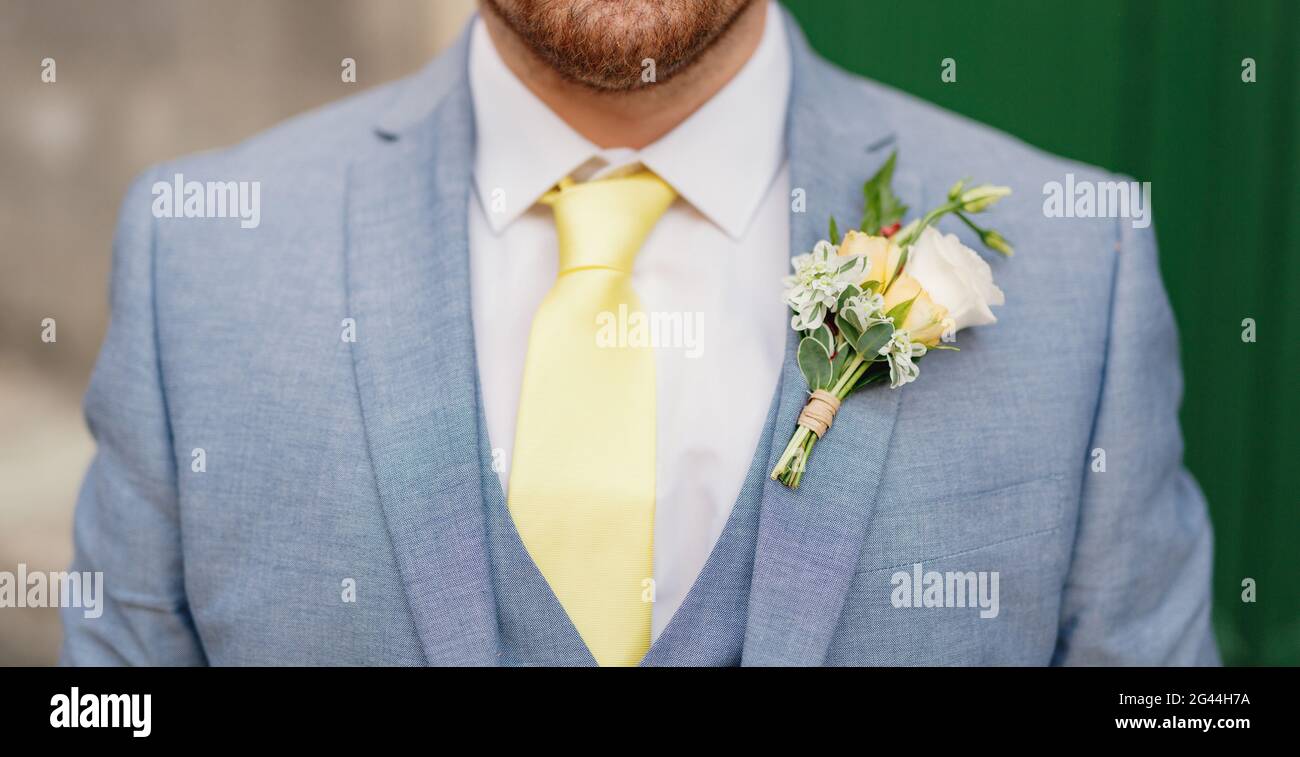 Uomo con stoppia in tuta blu con camicia bianca, cravatta gialla, gilet e boutonnière, primo piano Foto Stock