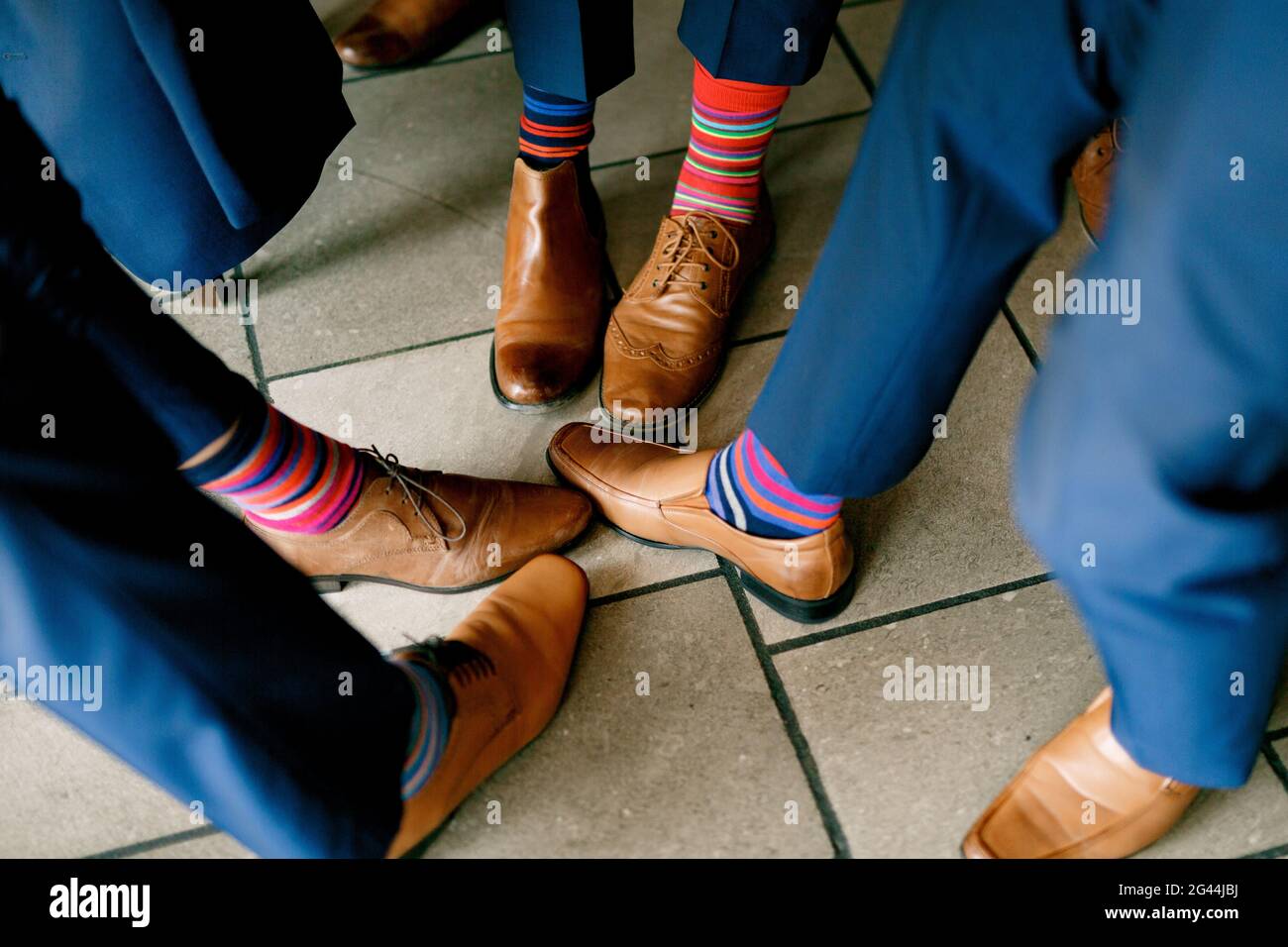 Gambe di uomini in pantaloni blu, scarpe in pelle e calze colorate a righe luminose, i testimoni dello sposo prima del matrimonio Foto Stock