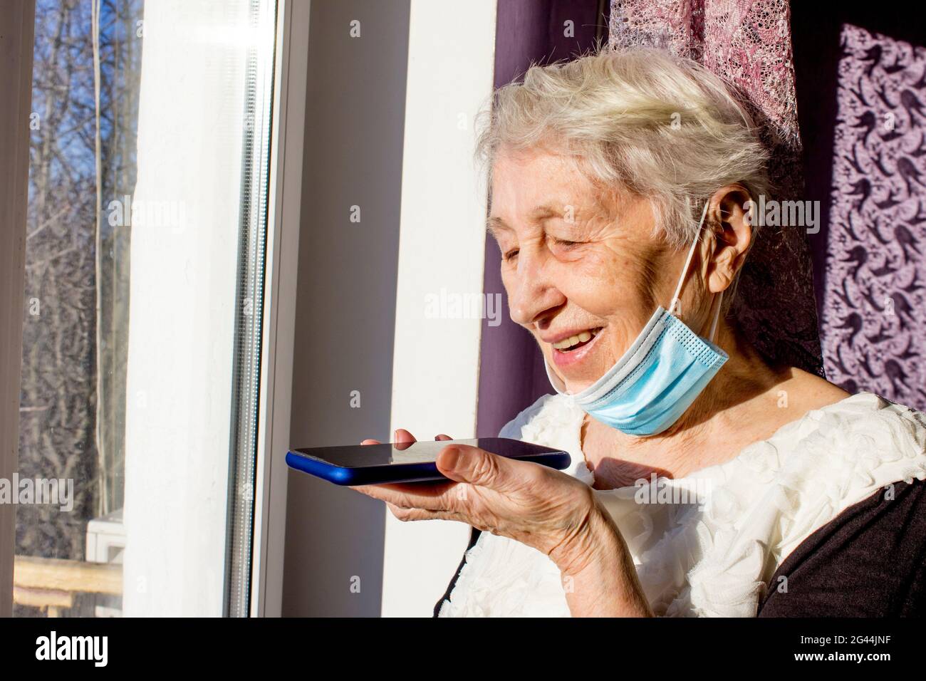 Nonna con smartphone che fa un messaggio audio sul gadget, donna matura che  usa il cellulare con assistente vocale digitale virtuale. Covid-19, salute,  pandemia - senior a casa per la protezione dal