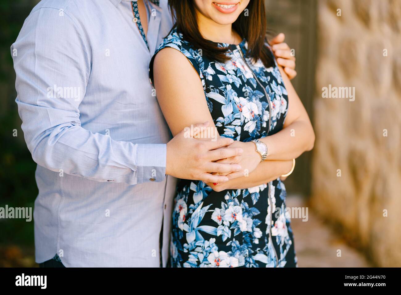 L'uomo in una camicia blu abbracca sorridente donna in un abito colorato Foto Stock L'uomo in una camicia blu abbracca sorridente donna in un abito colorato Foto Stock