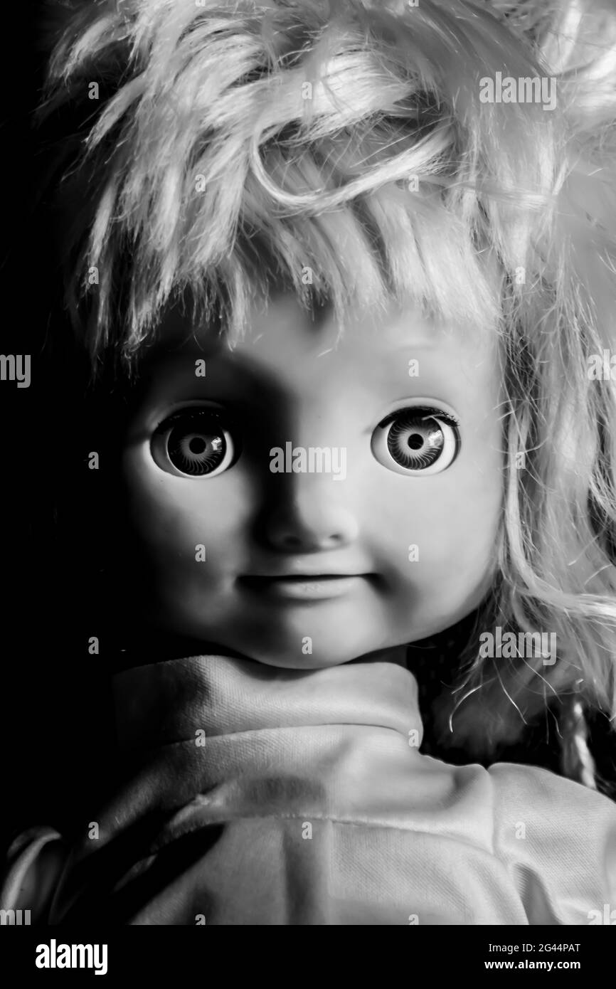 Faccia creepy della bambola della ragazza. Sembra un personaggio di film horror. Bambola infuriata, paura di un fantasma vivente. Concetto di Halloween. Nero Foto Stock