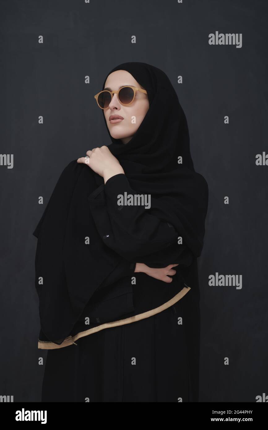 Giovane musulmano in abiti tradizionali o abaya e occhiali da sole in posa davanti alla lavagna nera Foto Stock