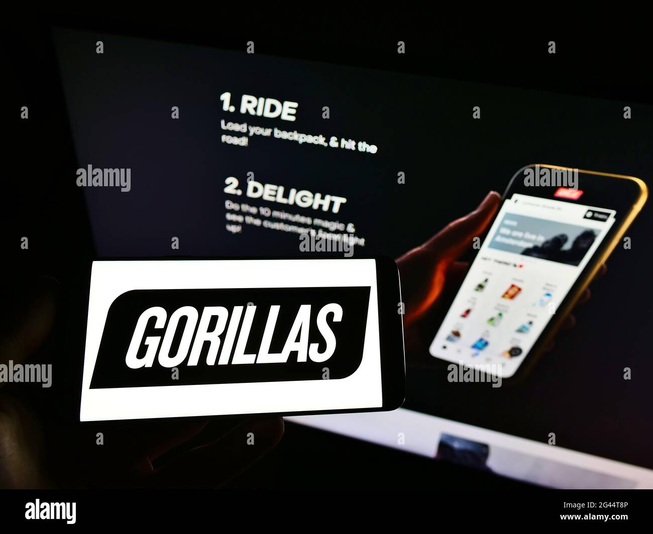 Persona che detiene il cellulare con il logo della società di consegna tedesca Gorillas Technologies GmbH sullo schermo di fronte alla pagina web. Mettere a fuoco il display del telefono. Foto Stock