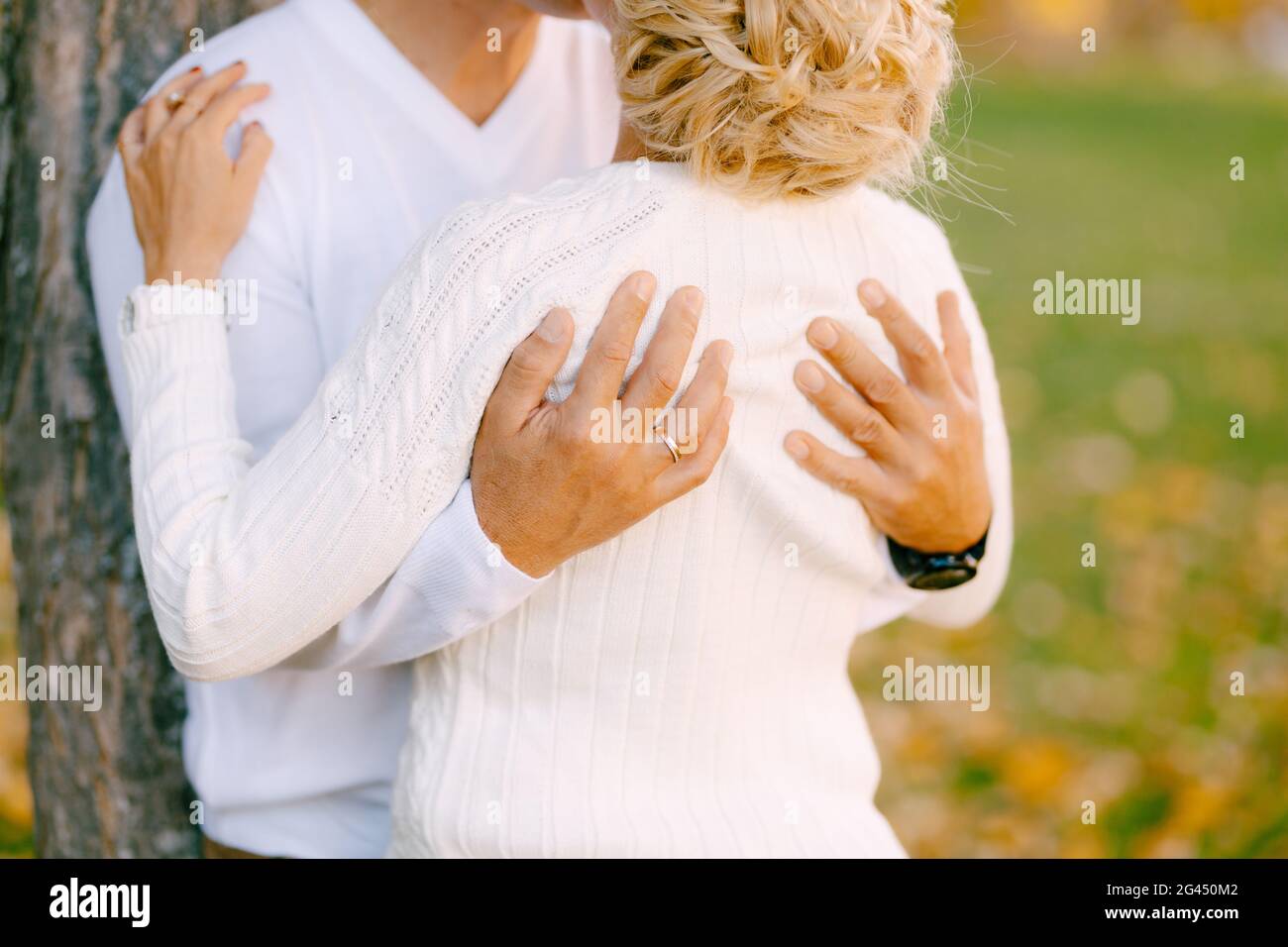 L'uomo abbraccia la donna alle spalle vicino ad un albero nella foresta d'autunno. Primo piano Foto Stock