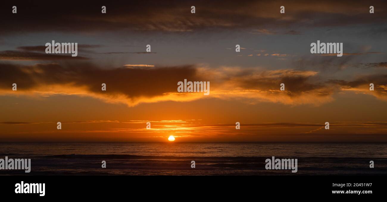 Cielo arancione Moody al tramonto sopra l'Oceano Pacifico Foto Stock