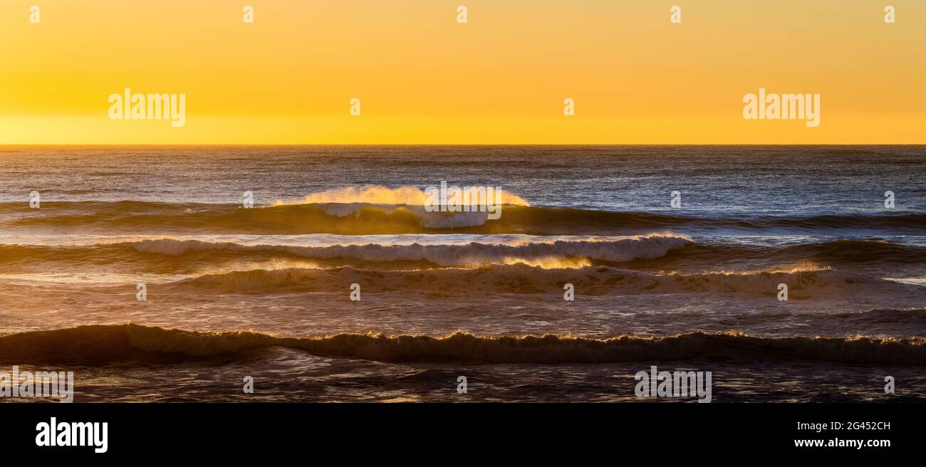 Onde che si infrangono in mare al tramonto Foto Stock