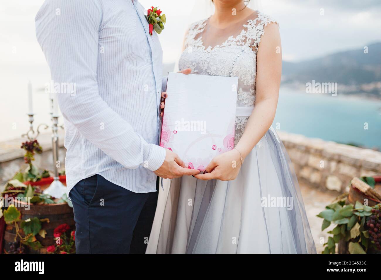 La sposa e lo sposo stanno abbracciando e tenendo un certificato di matrimonio nelle loro mani, primo piano Foto Stock