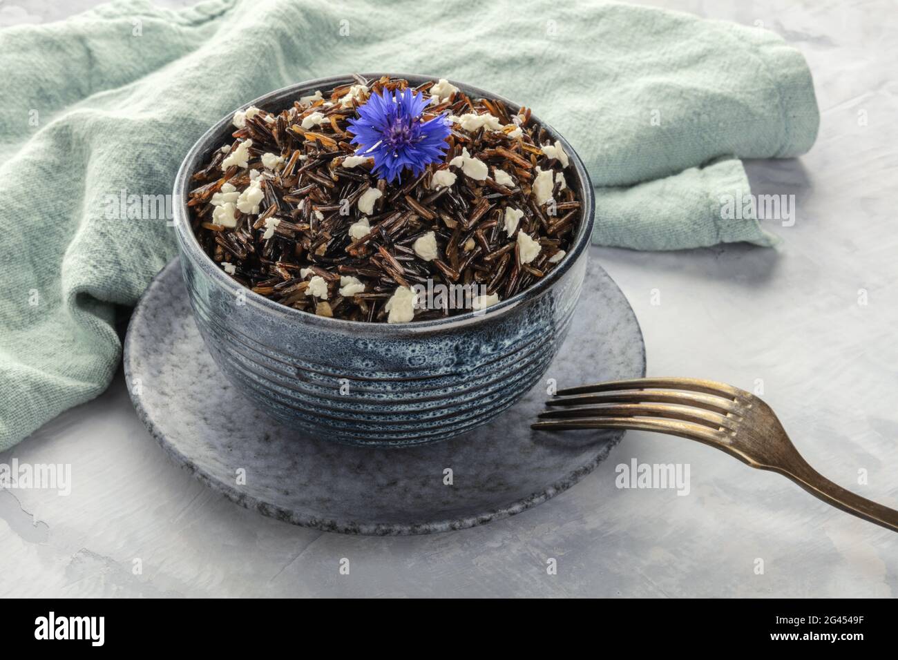 Riso nero selvatico con un formaggio Feta senza lattosio e un fiore commestibile Foto Stock