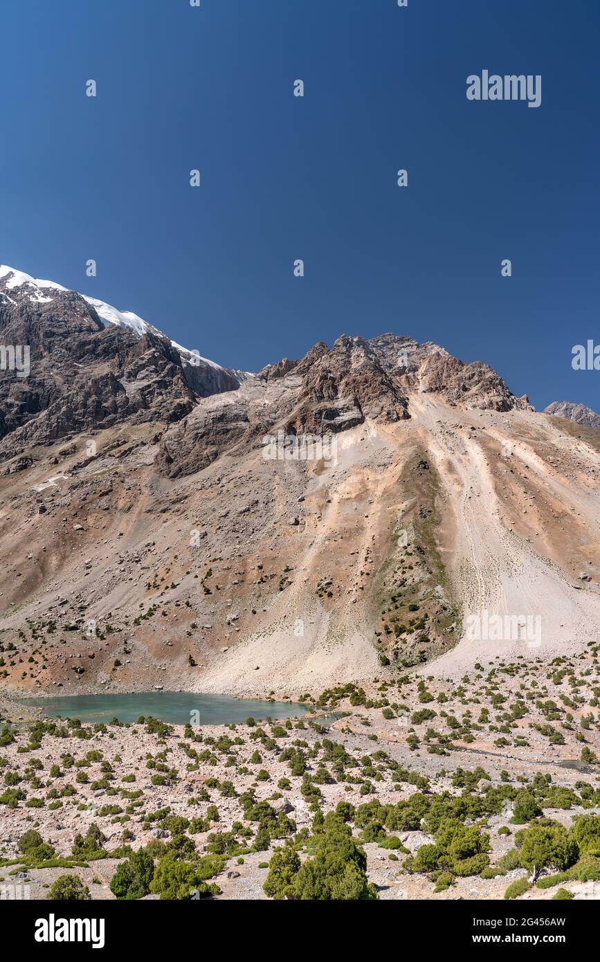 La splendida strada per il trekking in montagna con cielo azzurro e colline rocciose e il lago di montagna fresco nelle montagne di Fann in Tagikistan Foto Stock