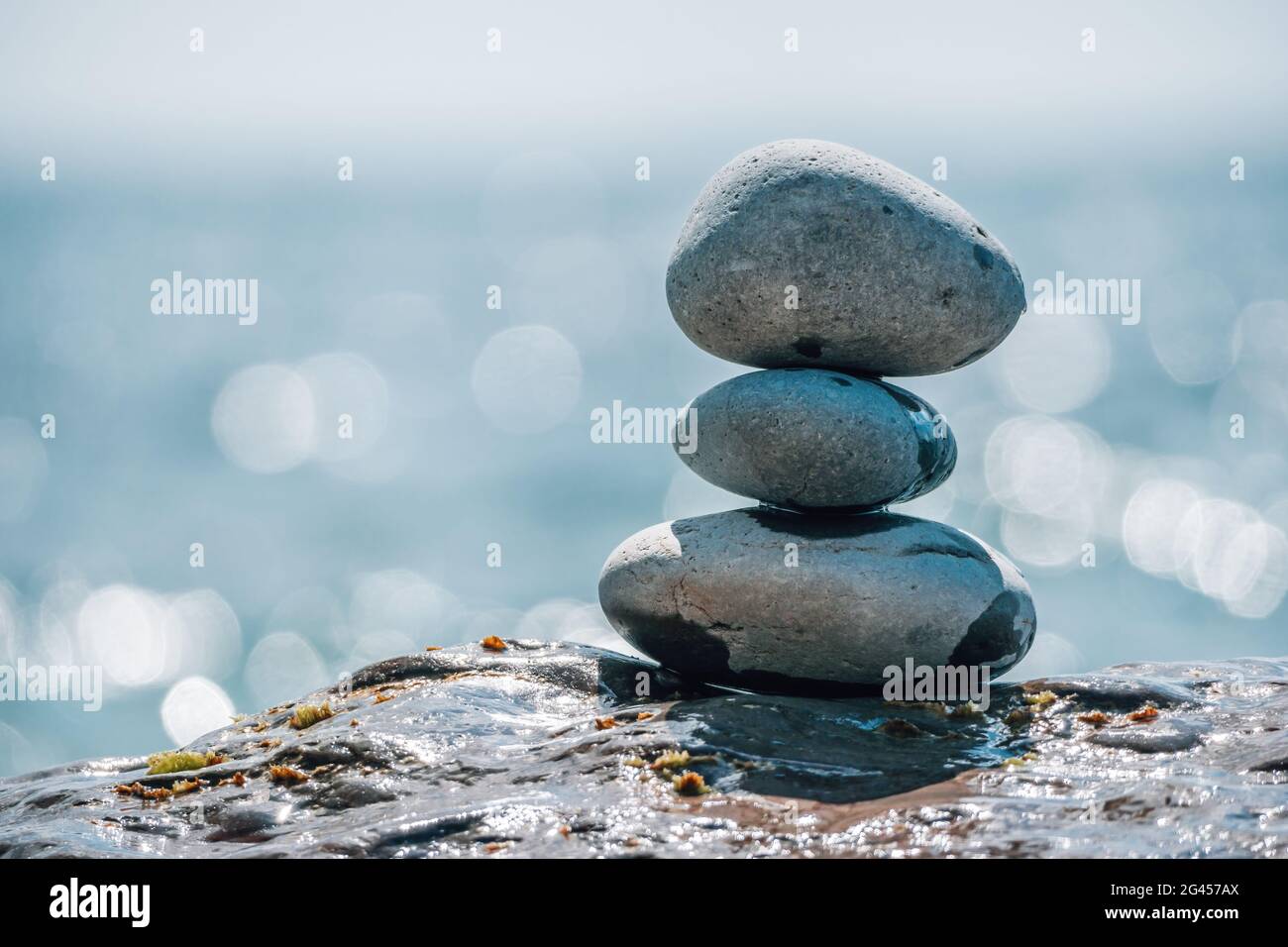 Equilibrata piramide di ciottoli sulla spiaggia in una giornata di sole. Abstract Sea bokeh sullo sfondo. Messa a fuoco selettiva. Pietre Zen sulla spiaggia di mare, meditazione Foto Stock