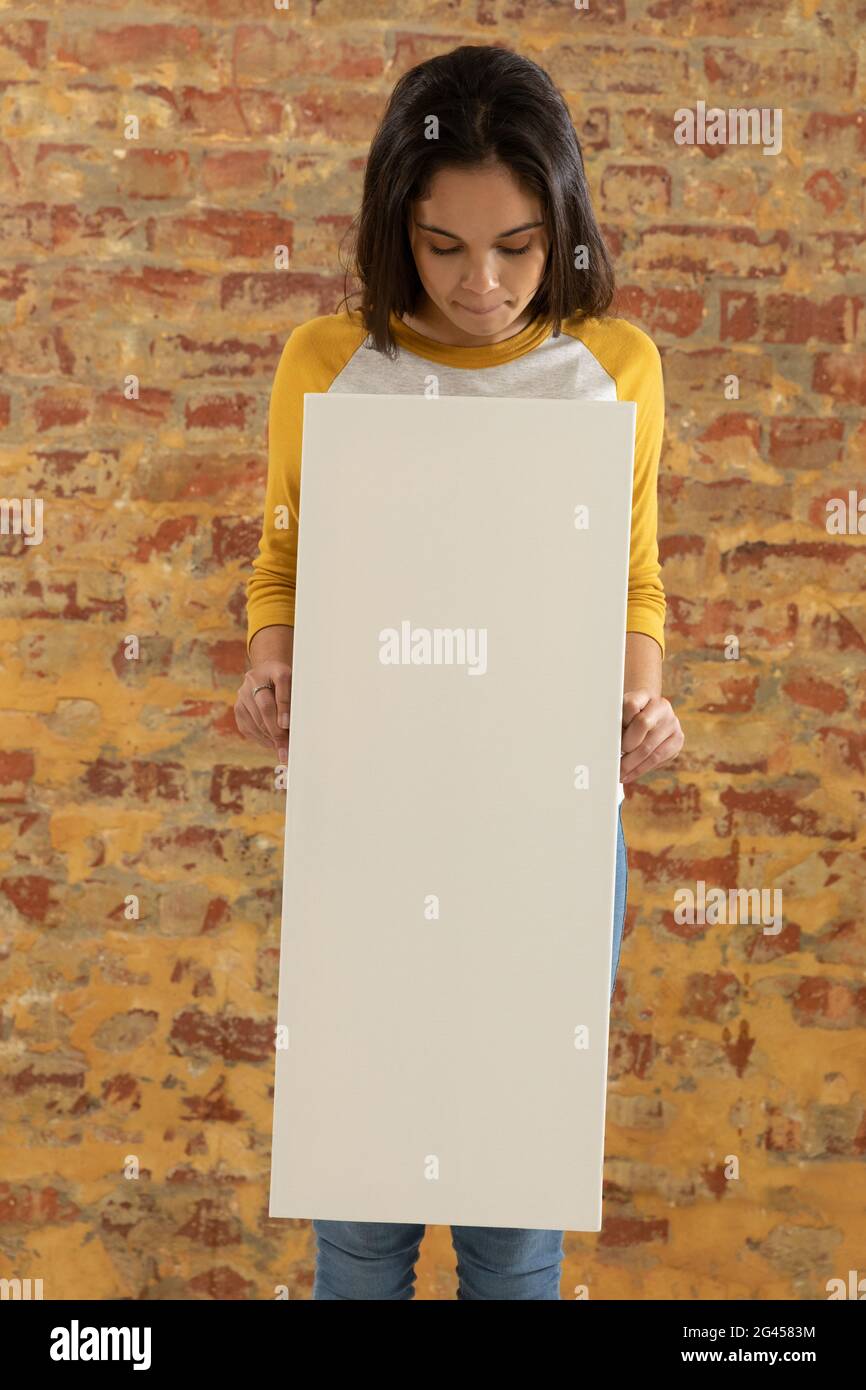 Tela vuota tenuto di fronte a un muro di mattoni Foto Stock