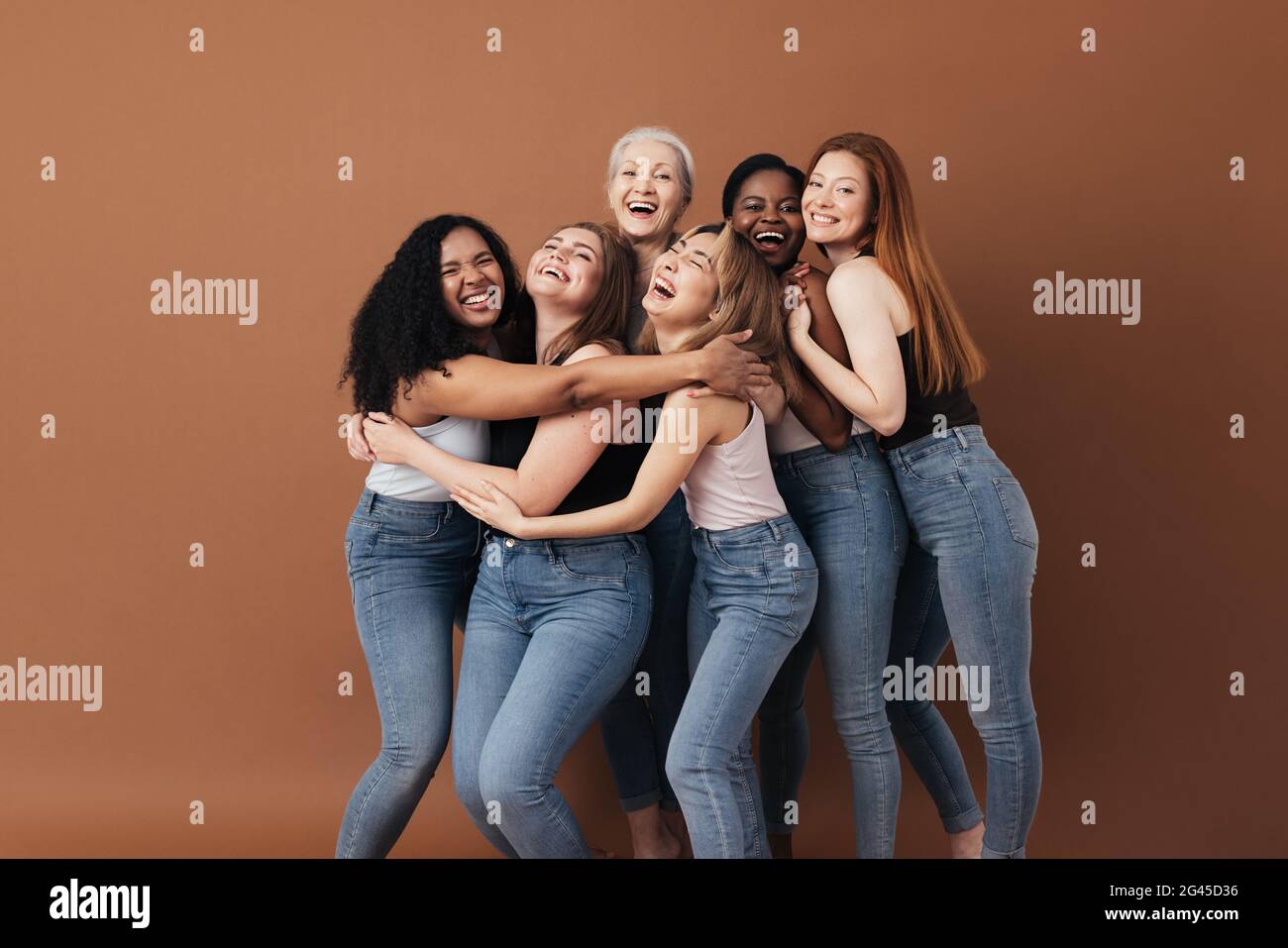 Sei donne ridenti di razza, età e tipo di figura diversi. Gruppo di femmine multirazziali che si divertono su uno sfondo marrone. Foto Stock