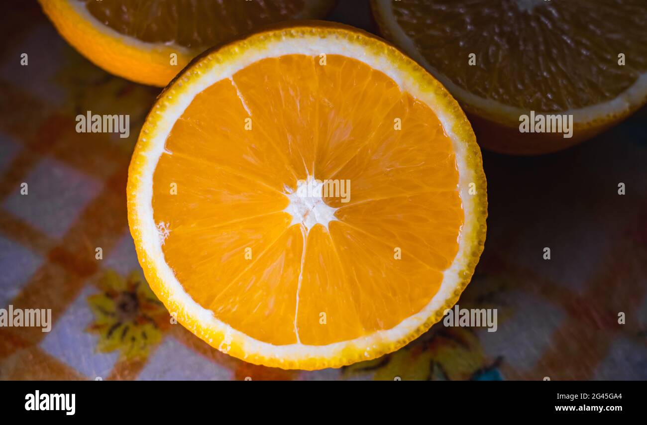 Primo piano di un arancio tagliato a metà e posto su un tagliere di plastica. Foto Stock