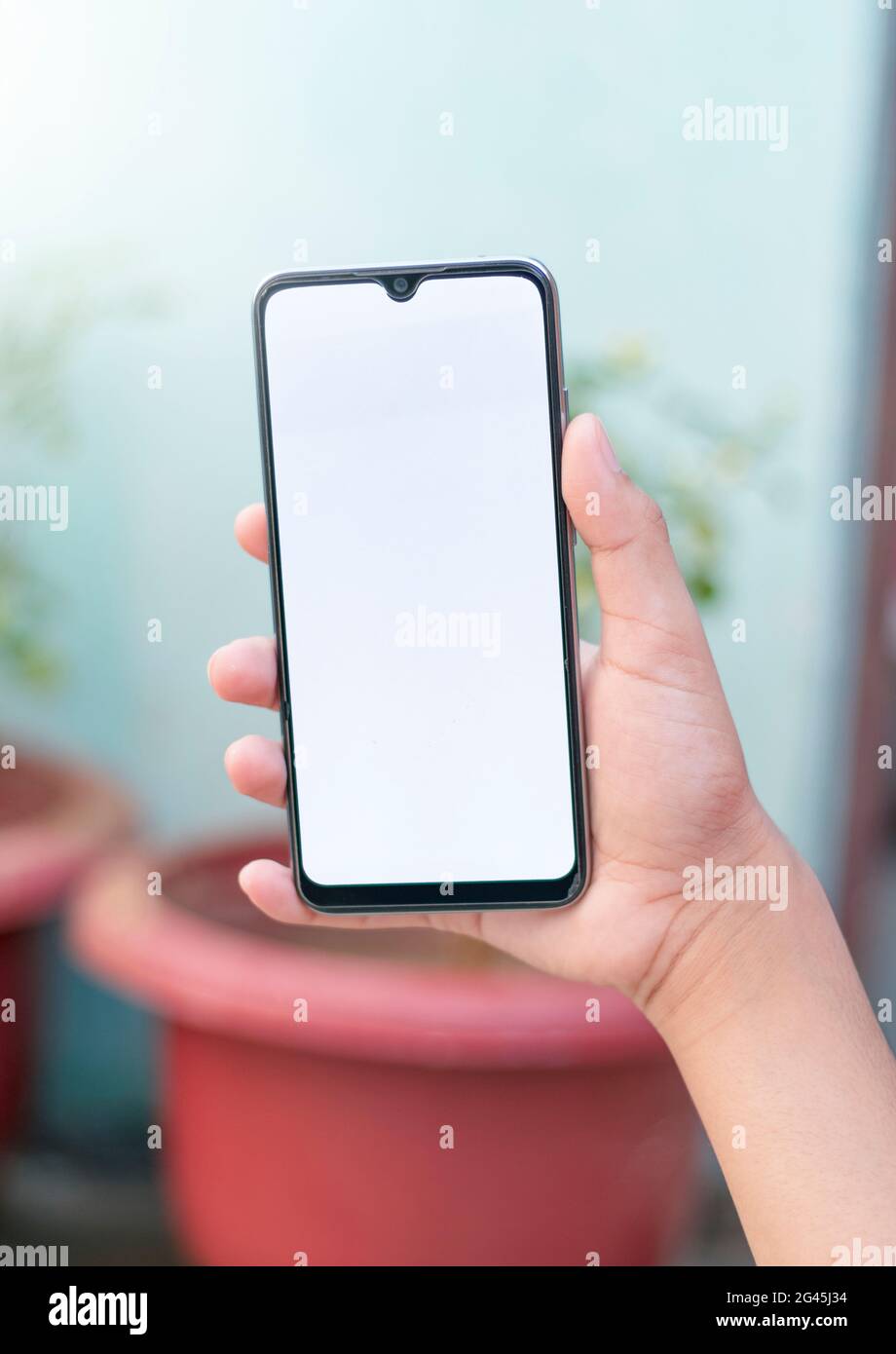 Uomo che tiene uno smartphone con schermo vuoto su sfondo bianco, primo piano della mano. Spazio per il testo. Foto Stock