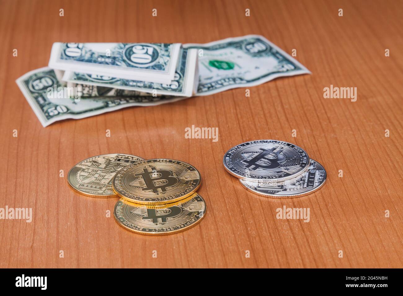Cryptocurrencies e 50 dollari di bollette sulla cima di un tavolo di legno. Le monete sono a fuoco e le fatture sono fuori fuoco. Foto Stock