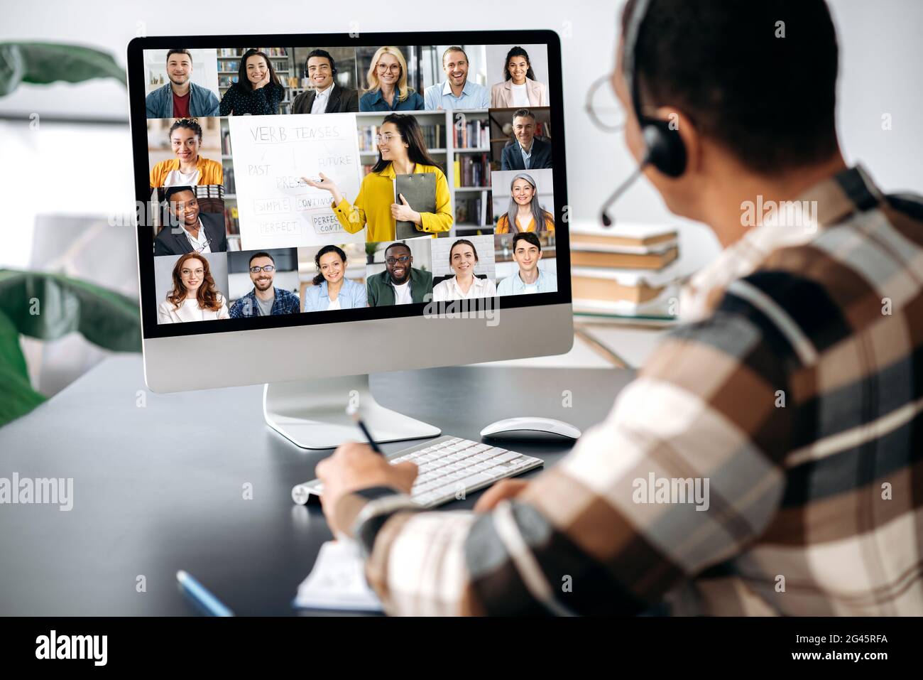 Apprendimento a distanza, formazione online. Vista sulla spalla di un ragazzo, uno schermo di computer con persone multirazziali, insegnante di sesso femminile conduce lezioni online per gli studenti tramite videochiamata, concetto di riunione virtuale Foto Stock