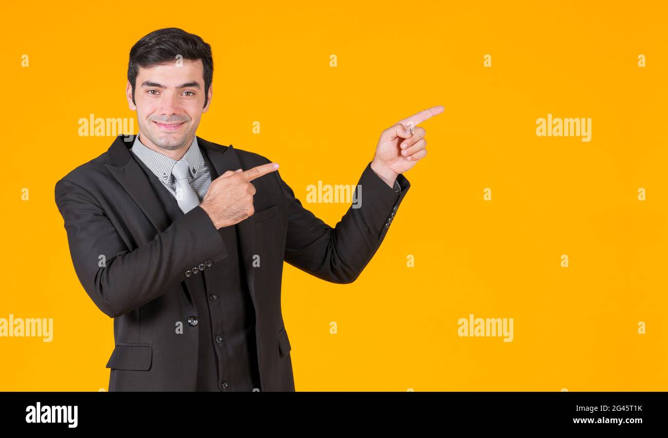 Giovane uomo d'affari caucasico in camicia grigia e un vestito nero che punta entrambe le dita nella stessa direzione. Mostra il progetto che sta per salire. Il Foto Stock