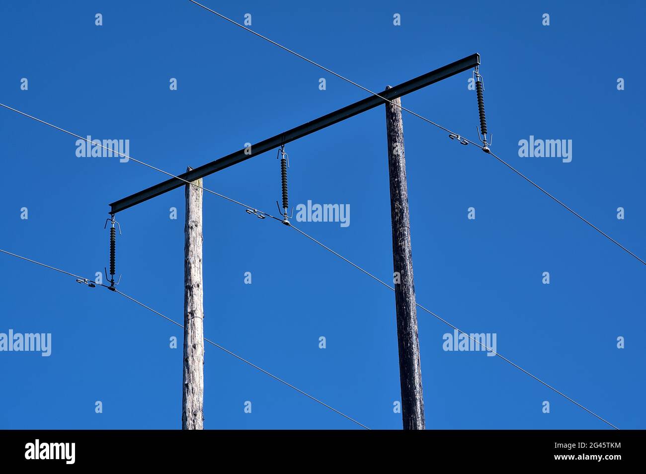 Bella vista luminosa delle linee elettriche aeree su vecchio pilastro di legno catturato contro cielo blu perfettamente chiaro, Ballycorus, Co. Dublino Foto Stock